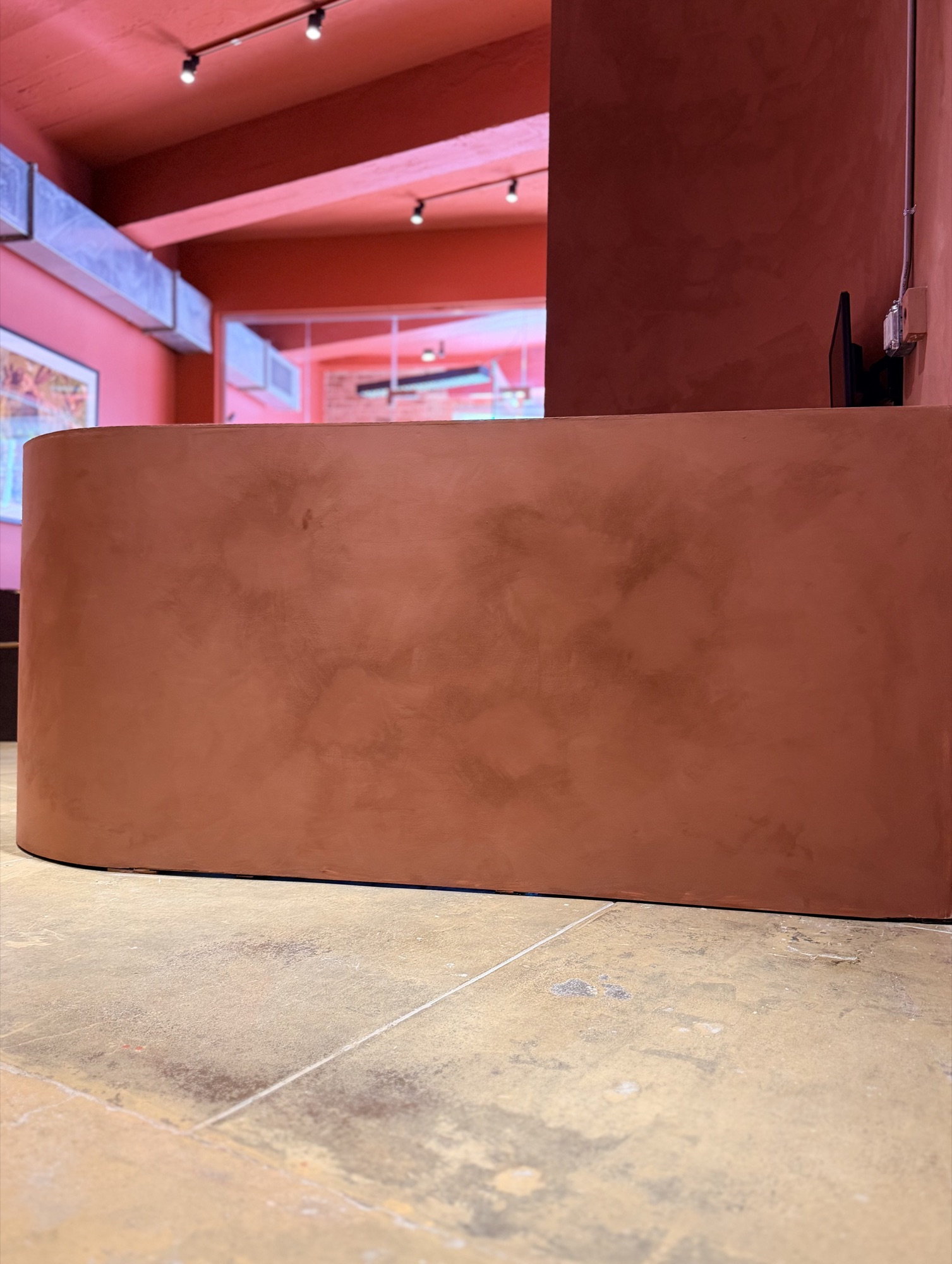 Finished terracotta limewash reception desk curving through a New York showroom